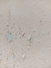 Peeling Paint on a Light Beige Wall. Close-up view of a light beige wall with significant peeling paint.