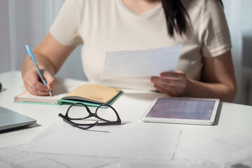 Fototapeta premium Female paying bills at home. Woman holding invoice in hands and calculates amount of debt. Bill payment online concept.