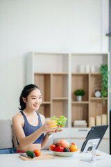 wellness as a cheerful woman enjoys a salad and fruits while engaging with technology at home