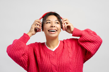 Young woman wearing red sweater enjoying music with wireless headphones