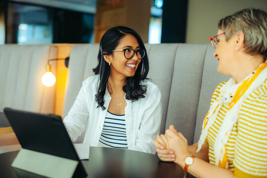 Smiling professor and PHD student engaging in a lively discussion at a cozy cafe