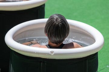Girl immersing herself in little Circular Pool Filled with Water and Ice: Ice Baths and Wellness