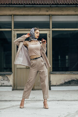 young woman standing on the street in front of a building with large windows.