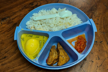 Rice side dishes in a blue Tupperware lunch box on the table