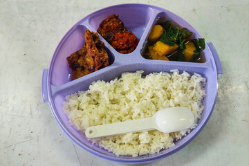 Rice side dishes in a blue Tupperware lunch box on the table