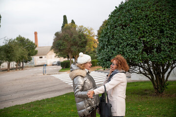 Fototapeta premium Two senior women laughing and playing together in a park during a village tour in Spain