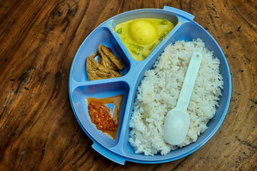 Rice side dishes in a blue Tupperware lunch box on the table