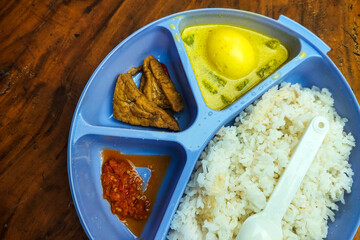 Rice side dishes in a blue Tupperware lunch box on the table