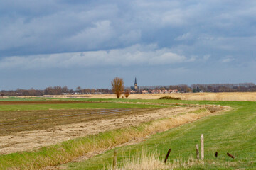 Rural Dutch landscape, fields of varying colors, and a small town with church spire.  Cloudy sky...