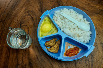 Rice side dishes in a blue Tupperware lunch box on the table