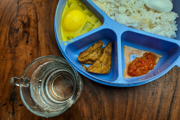 Rice side dishes in a blue Tupperware lunch box on the table