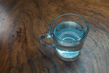 Water in a glass on a wooden table, suitable for the background