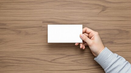 Obraz premium Hand-holding business card mockup, blank white card, wooden desk background