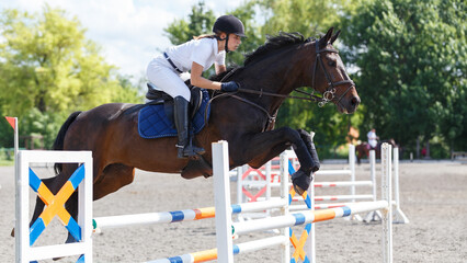 Female equestrian rider jumps over obstacles during a show jumping event