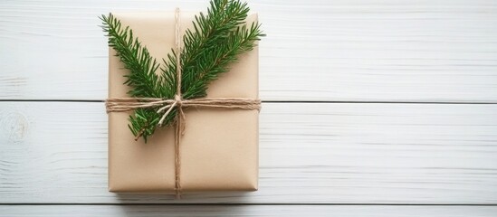 Christmas gift wrapped with twine and fir branches on white wooden table background Overhead view with copy space for holiday greetings