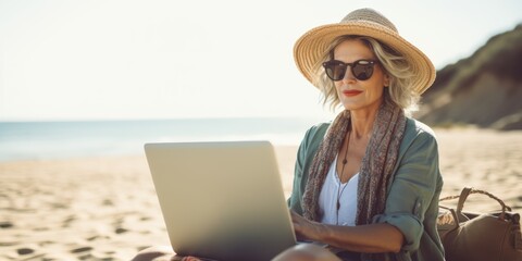 Fototapeta premium Attractive mature woman 50-60 makes use of laptop on the seashore, active elderly people, Generative AI.