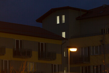 A tall building stands majestically with a bright street light illuminating the front of it during the serene night hours, creating a cozy ambiance