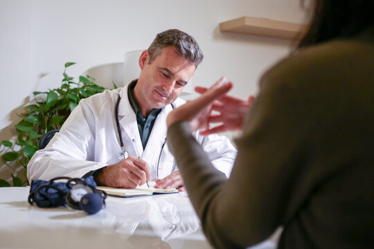 A male doctor consulting in his private office and reviewing patient reports.