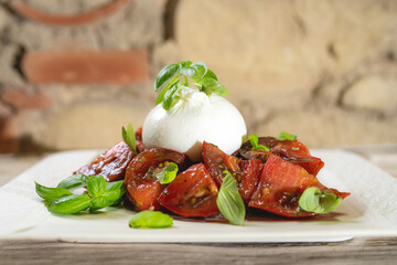 Homemade breakfast food, ripe tomatoes with tender burrata and basil. Light background.