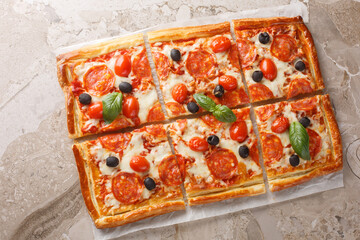 Spicy tart pizza made from puff pastry with pepperoni sausage, olives, cheese and tomato sauce...