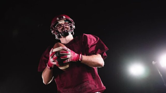 An American football player practicing throwing and catching the ball on a field