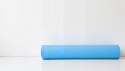 Blue yoga mat lying on a white surface with copy space