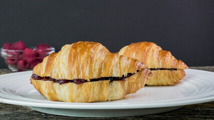 Two croissants filled with jam on a white plate
