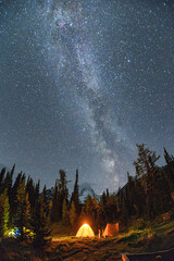 Landscape of Milky way over mount Assiniboine with illuminated tent camping in autumn forest at...