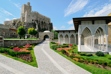 Fototapeta premium Historic Rabat Castle with Golden Dome, White Arches, and Lush Gardens Featuring Fountains Pools and beautiful colorful flowers surrounding old wall