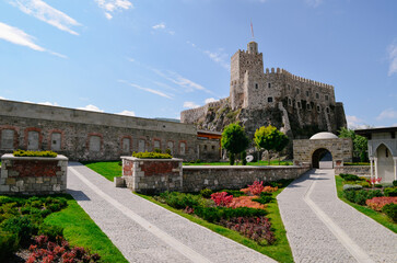 Obraz premium Historic Rabat Castle with Golden Dome, White Arches, and Lush Gardens Featuring Fountains Pools and beautiful colorful flowers surrounding old wall