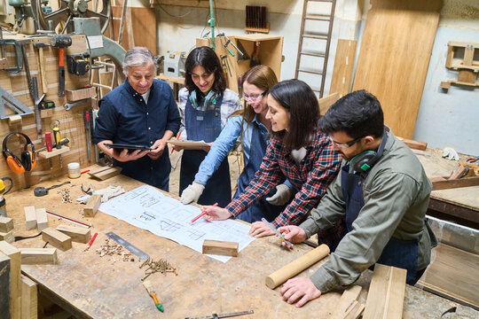 Young apprentices learning carpentry skills in a collaborative workshop setting
