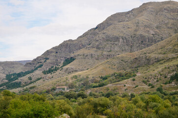 Fototapeta premium Mountainous Landscape with Buildings in a Valley and Cloudy Sky