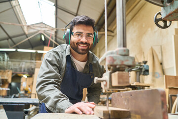 Confident carpenter working with machinery in a busy lumberyard