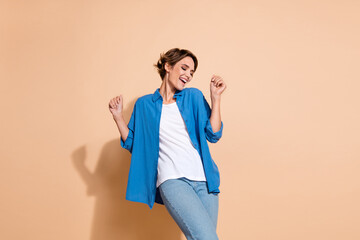 Photo of young positive businesswoman dancing wear blue shirt feeling happy when started own business isolated on beige color background
