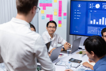 Analyst team utilizing BI Fintech to analyze financial data at table in meeting room. Businesspeople analyzing BI dashboard power for business insight and strategic marketing planning. Prudent