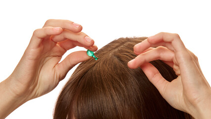 Fototapeta premium Close-up of woman applying serum capsule on her head skin, hair against white studio background. Treatment, nourishment. Concept of natural beauty, hair care, cosmetics and cosmetology