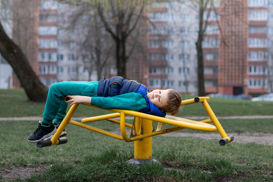 Little boy having fun on exercise machine at park.