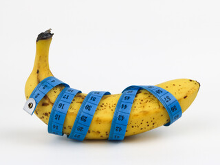 Yellow banana with measurement tape on white background. Male genitalia size concept