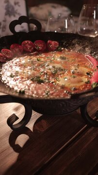 Vertical closeup footage of a person serving fresh Shakshouka on dining table