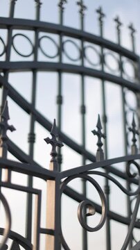 Vertical closeup detailed view of wrought iron gate against clear sky background.