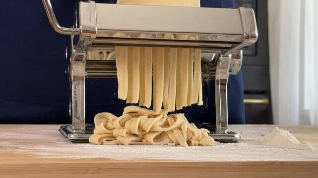Crafting fresh pasta with a manual pasta maker in a kitchen setting. preparing pasta
