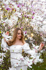 Fototapeta premium Magnolia. Magnolia Tree Garden. Young beautiful girl in magnolia tree flowers.