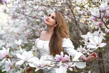 Fototapeta premium Magnolia. Magnolia Tree Garden. Young beautiful girl in magnolia tree flowers.