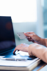 woman holding credit card, and typing on laptop, to shop, and pay via internet, concept of online shopping and services, ordering products at home.