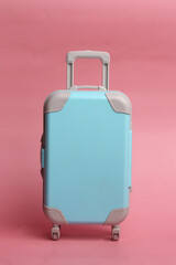 blue suitcase on pink background