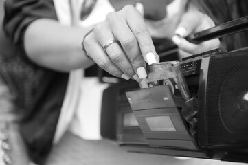 The girl inserts a cassette into the tape recorder.
