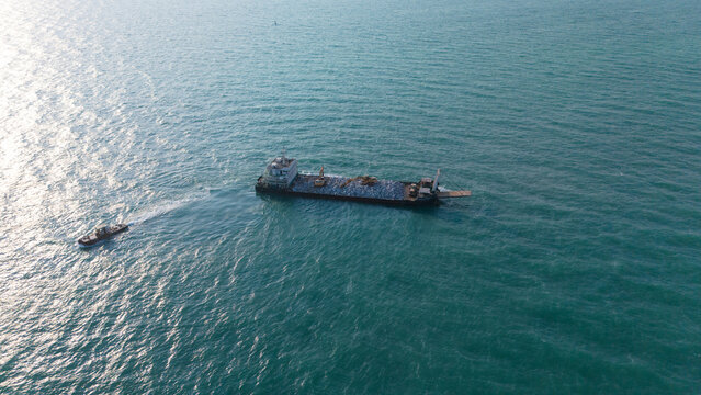 A ship is carrying a backhoe in the sea.
