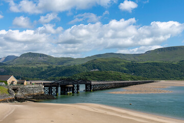 Panoramic view over sandbanks in the Mawddach Estuary near Barmouth, UK  with wooden Barmouth single-track railway viaduct and longest timber viaduct in Wales