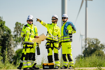 Teamwork four young male wind farm engineers work inspecting field systems.Wind turbine engineer inspection and wind turbine inspection progress at construction site.