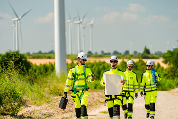 Teamwork four young male wind farm engineers work inspecting field systems.Wind turbine engineer inspection and wind turbine inspection progress at construction site.